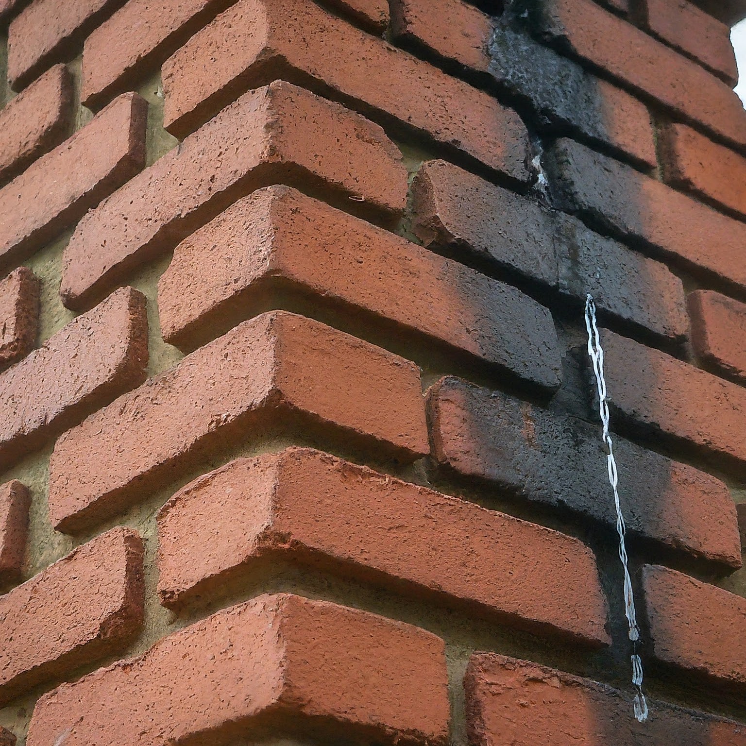 a damaged chimney crown with cracks and holes, allowing water to seep through. This can cause leaks inside the house.
