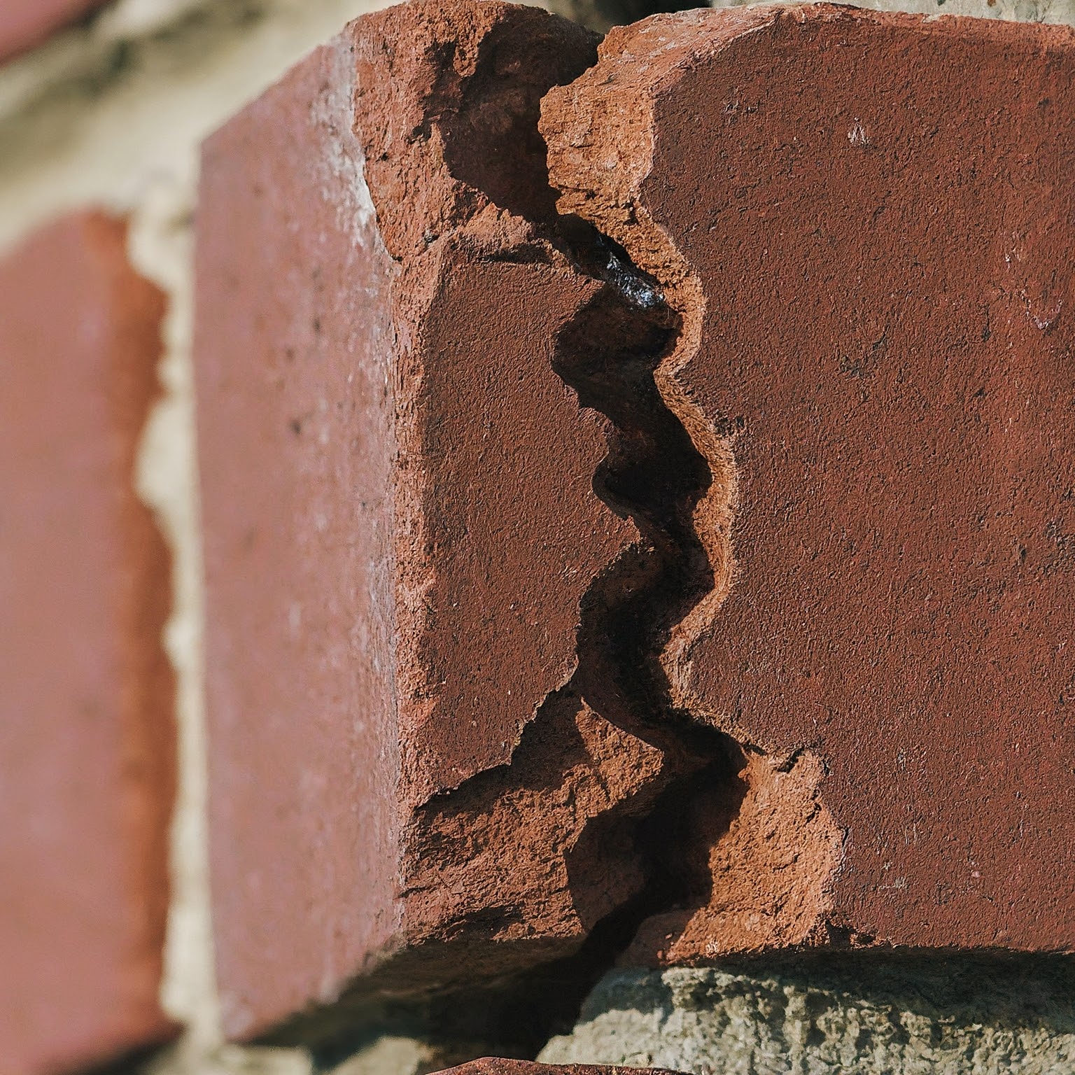 A brick chimney damaged by the freeze-thaw cycle, showing cracks and spalling brickwork. This emphasizes the impact of harsh Minnesota winters on masonry structures.